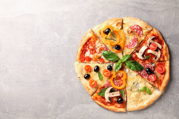 Heerlijke pizza met verschillende stukken op grijze achtergrond, ruimte  - Foto, afbeelding