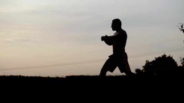 Silhouette eines starken Sportlers macht eine Atemübung allein bei Sonnenuntergang und meditiert bei Sonnenuntergang - Filmmaterial, Video