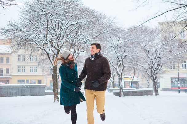 ευτυχισμένο νεαρό ζευγάρι που περπατάει στο κέντρο της πόλης για τις διακοπές των Χριστουγέννων - Φωτογραφία, εικόνα