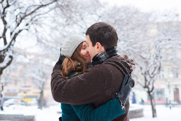 Ekose eşarplar giymiş genç seven çift kışın eski şehirde yürümek. Sarılma ve öpüşme - Fotoğraf, Görsel