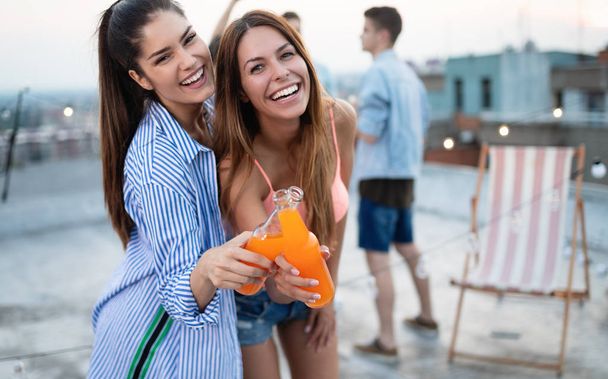 Beautiful young women friends on the balcony having fun at party. - 写真・画像