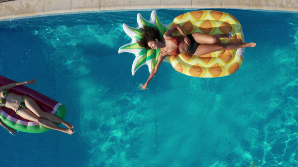 Вид зверху на радісних дівчат, що лежать на флягах у басейні
 - Кадри, відео