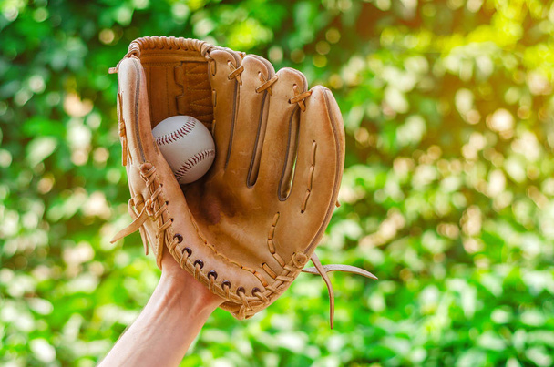Mano masculina en un guante de cuero de béisbol atrapó una pelota en un b verde
 - Foto, imagen