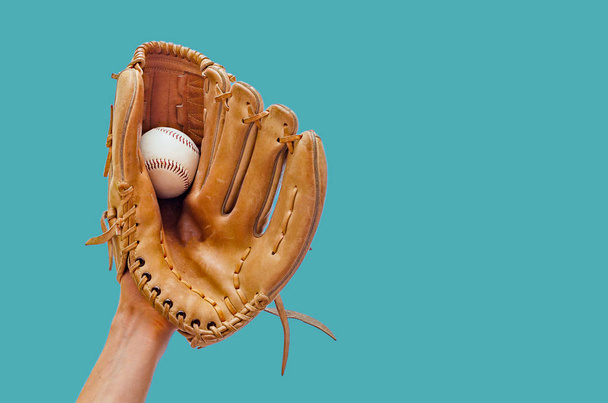Hand in einem ledernen Baseballhandschuh fing einen Ball auf grünem Hintergrund ein - Foto, Bild