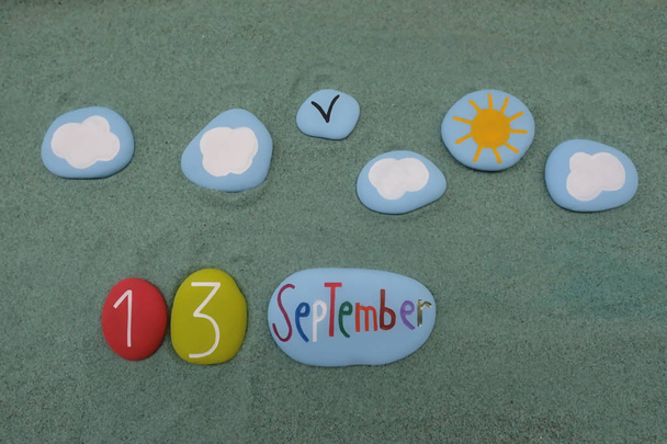 13 de septiembre, fecha del calendario compuesta por letras y números de piedra de color rojo sobre arena verde - Foto, imagen