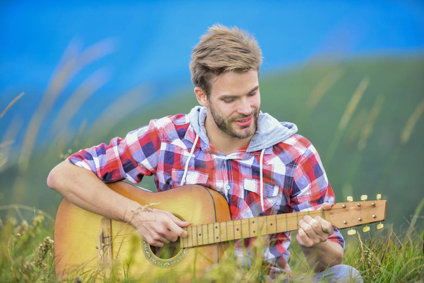 Hiking song. Man musician with guitar on top mountain. Inspired musician. Hipster musician. Inspiring environment. Summer music festival outdoors. Silence of mountains and sound of guitar strings - Foto, afbeelding