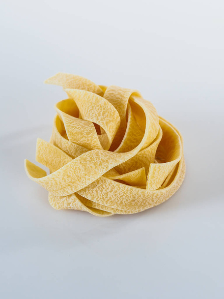 Raaka tagliatelle pasta eristetty valkoisella taustalla. - Valokuva, kuva