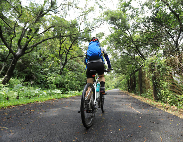 Nő kerékpáros lovaglás Mountain Bike a trópusi esőerdő nyomvonal - Fotó, kép