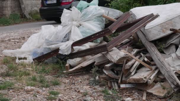 Samochody na drodze przez śmieci po cenach dumpingowych: deski, materac, pocieszyciel, plastikowe torby pełne śmieci - Materiał filmowy, wideo