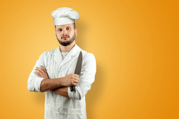 Man with a beard, a cook in a hat and a knife in his hand Isolated on a yellow background. Cooking, recipes, cuisine. - Fotoğraf, Görsel