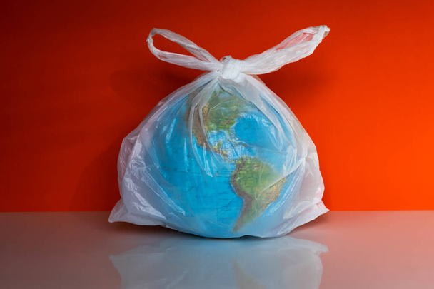 Earth globe in plastic bag on grey background - Foto, immagini