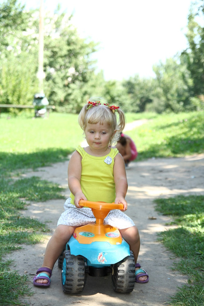 Little girl driving her toy car in the park, outdoors - Foto, imagen