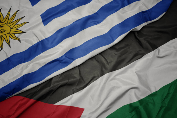 machając kolorowy flaga Palestyny i flagi narodowej Urugwaju. - Zdjęcie, obraz