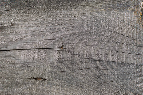 Old gray-brown natural wood background in the form of a board with cracks, knots and a rough surface - Φωτογραφία, εικόνα