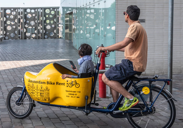 Bakfiets or front-trunk bike on the move in Amsterdam Netherland - Foto, immagini