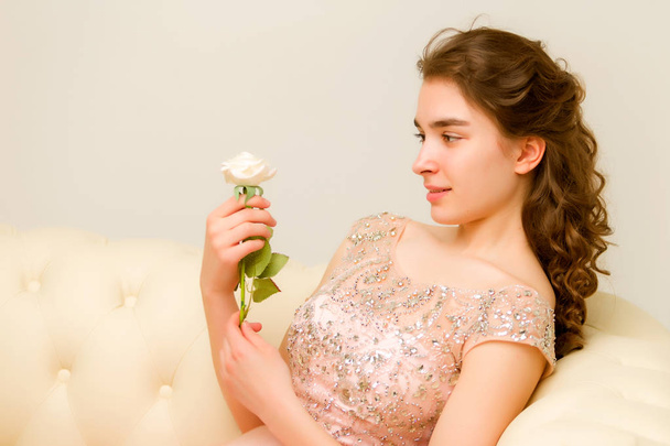 Teen girl sitting on the couch holding a flower in her hand. - Foto, immagini