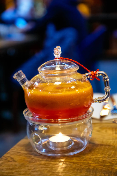 Red tea with sea buckthorn in a glass teapot. - Foto, Imagen