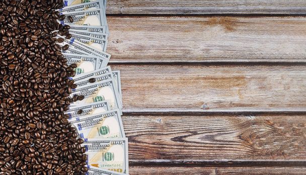 Банкнота 100 американских долларов, между кофейными зернами, продажа, доставка и распространение кофе на деревянном фоне
 - Фото, изображение