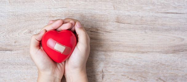 Γυναίκα που κρατά κόκκινο σχήμα καρδιάς σε ξύλινο φόντο. Υγειονομικής περίθαλψης,  - Φωτογραφία, εικόνα