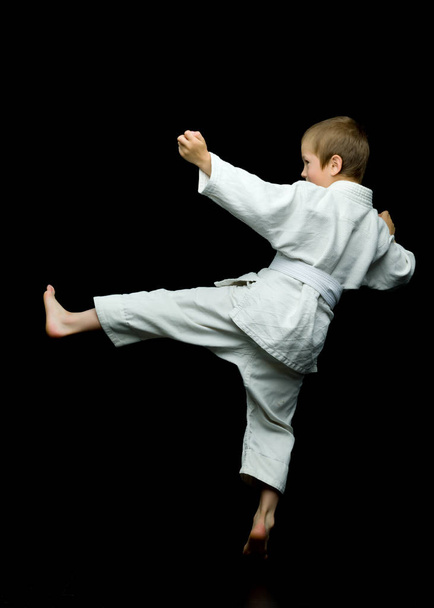 A little boy in a white kimono fulfills blows - Foto, immagini