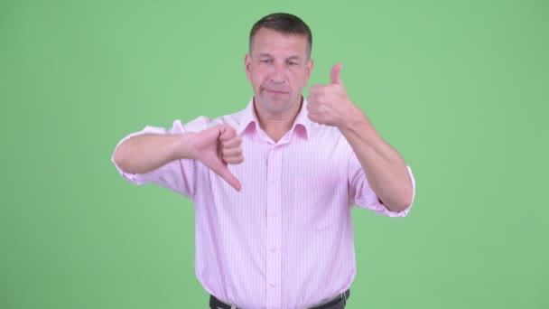 Verward volwassen macho zakenman kiezen tussen duim omhoog en duimen naar beneden - Video