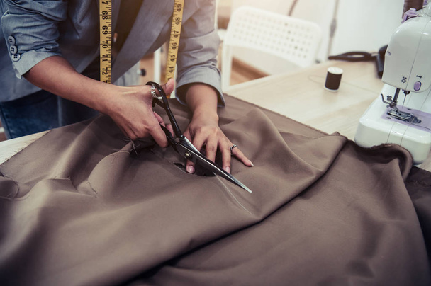 Dressmaker cutting dress fabric on sketch line with sewing machi - Fotoğraf, Görsel