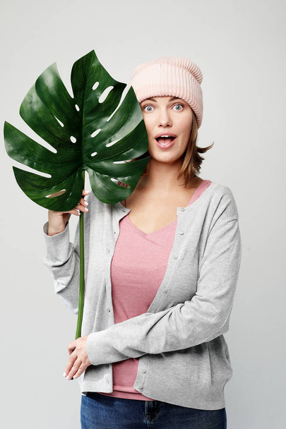 young woman holding a leaf of a large tropical flower and smiling - Fotografie, Obrázek