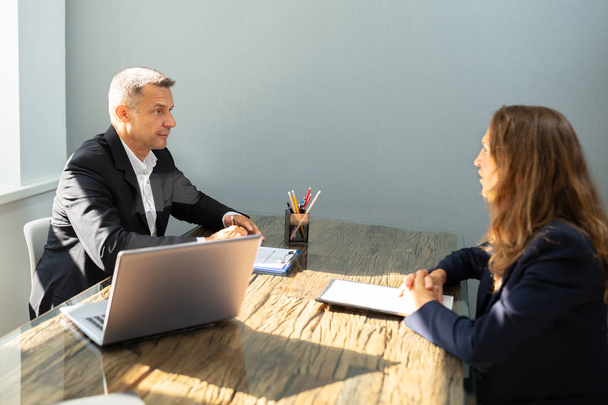 Reifer Geschäftsmann interviewt Frau über den Holztisch im Büro - Foto, Bild