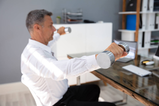 Businessman Exercising With Dumbbells In Office During Break - Fotó, kép