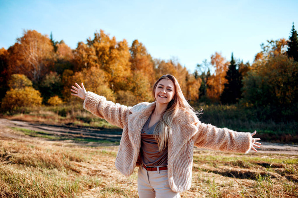 Wesoła dziewczyna z podniesioną dłonią na boisku w ciepłym sezonie jesiennym. - Zdjęcie, obraz
