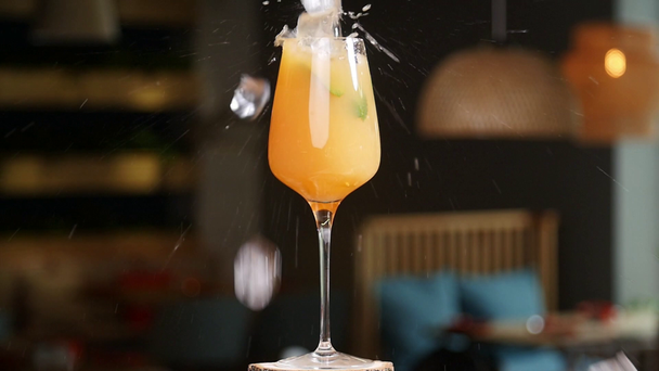 Essen und Trinken. Eiswürfel, die in einen spritzenden Orangencocktail fallen - Filmmaterial, Video