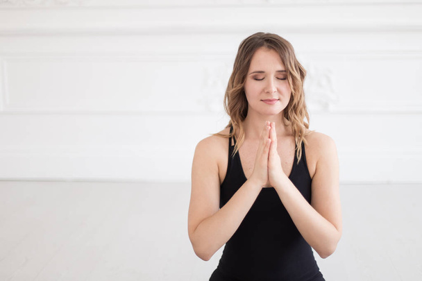 Charming woman in sport outfit holds her hands in praying gesture - Photo, Image
