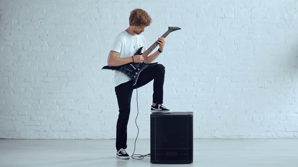 mladý, který hraje elektrickou kytaru poblíž reproduktoru - Záběry, video