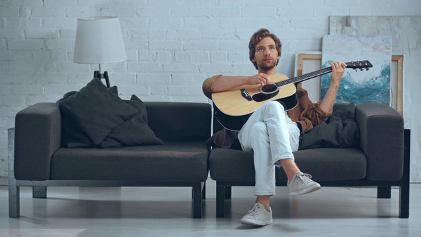 jonge roodharige man speelt akoestische gitaar op de Bank - Video