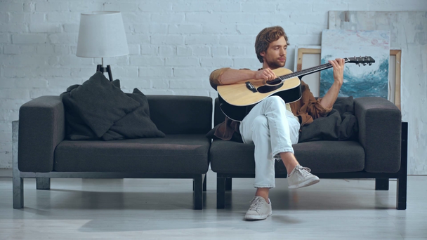 jonge man speelt akoestische gitaar op de Bank - Video