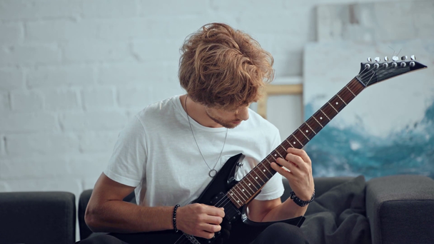 roqueiro sorridente tocando guitarra elétrica no sofá
 - Filmagem, Vídeo