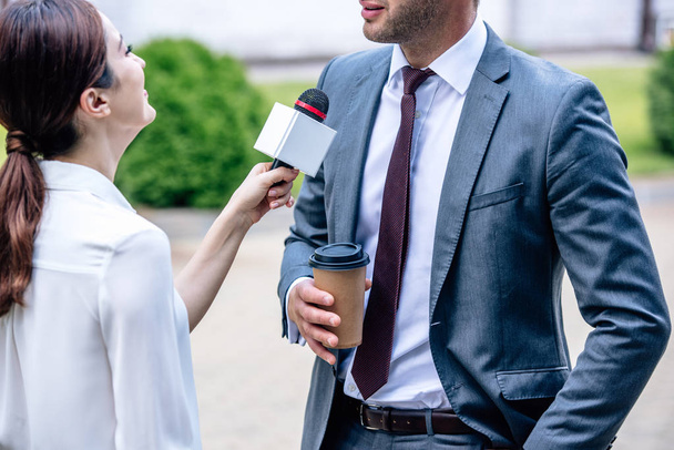 journalist houdt microfoon en praat met zakenman in formele slijtage  - Foto, afbeelding