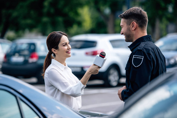 gazeteci mikrofon tutan ve üniformalı yakışıklı polis ile konuşurken - Fotoğraf, Görsel