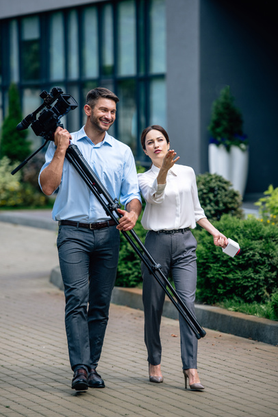 ελκυστική δημοσιογράφος κρατώντας μικρόφωνο και εικονολήπτη κρατώντας ψηφιακή βιντεοκάμερα - Φωτογραφία, εικόνα
