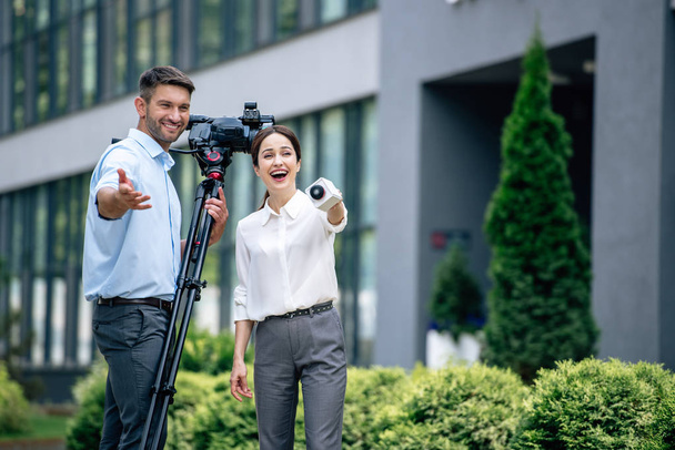 привлекательный журналист с микрофоном и оператором, держащий цифровую видеокамеру
 - Фото, изображение