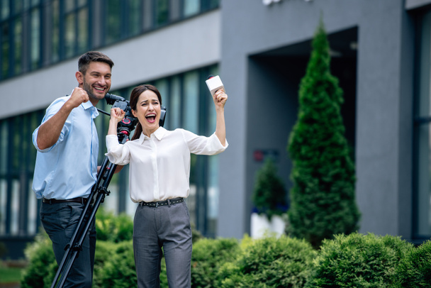attractive journalist holding microphone and cameraman holding digital video camera - Foto, Imagem