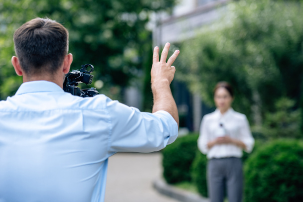 selective focus of cameraman shooting showing gesture and shooting journalist  - Zdjęcie, obraz