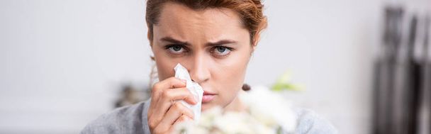 inyección panorámica de mujer enferma con alergia al polen sosteniendo tejido cerca de las flores
  - Foto, Imagen