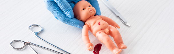 tiro panorámico de médico en guantes de látex azul sosteniendo muñeca con sangre cerca de instrumentos médicos
  - Foto, Imagen