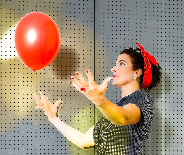 vrouw aantrekkelijk vrolijke senior vrouw spelen met rode ballon binnen - Foto, afbeelding