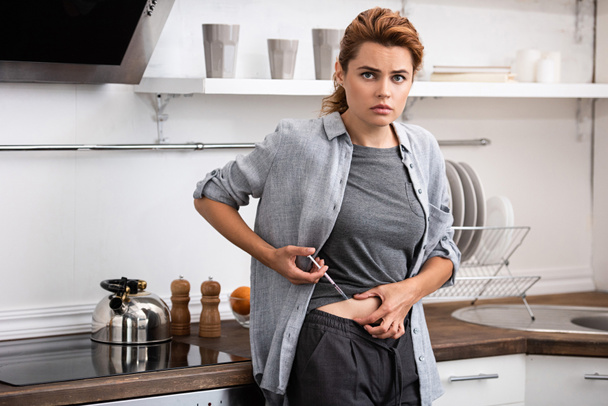 attraente donna in piedi in cucina e fare l'iniezione con siringa
  - Foto, immagini
