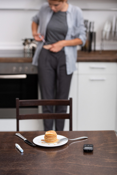 selective focus of tasty pancakes near medical equipment and woman in kitchen  - Photo, Image