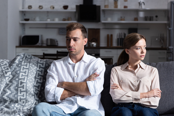 pensive sad man and woman sitting on sofa with crossed arms - Foto, imagen