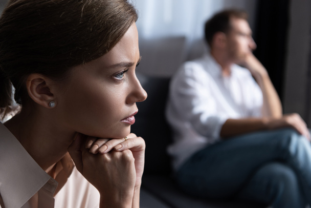upset pensive young woman and husband sitting on sofa - Zdjęcie, obraz