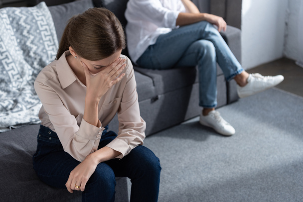 partial view of upset couple sitting on sofa in living room - Photo, Image